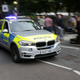 A police BMW X5 passes a crowd.
